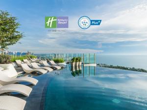 华欣华欣瓦纳纳瓦假日度假酒店的一座带白色椅子的游泳池,其背景是大海