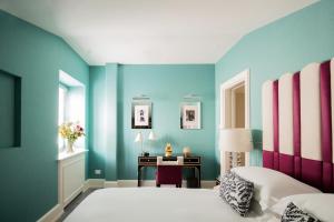 罗马Maalot Roma - Small Luxury Hotels of the World的一间卧室设有蓝色的墙壁和一张带书桌的床。