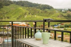 Kampung Kuala TerlaGorgeous Sunset & Tea Plantation View-Premium Hotel Bed的阳台上的桌子和花瓶,杯子