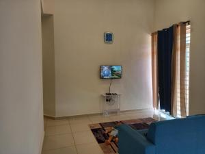 宜力Homestay Zaki D'Gerik的客厅配有蓝色的沙发和墙上的电视