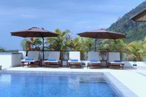 高兰Kulraya Villas - Luxury Serviced Pool Villas的游泳池旁的游泳池配有椅子和遮阳伞