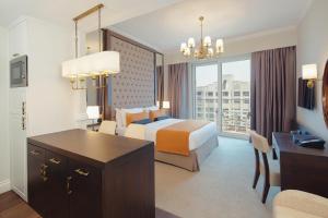 迪拜Dukes The Palm, a Royal Hideaway Hotel的配有一张床和一张书桌的酒店客房