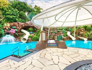 新加坡Shangri-La Rasa Sentosa, Singapore的主题公园的游泳池,配有遮阳伞和水滑梯