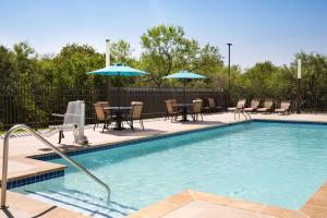 圣安东尼奥La Quinta Inn & Suites by Wyndham San Antonio Seaworld LAFB的一个带桌椅和遮阳伞的游泳池