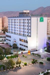 马斯喀特马斯喀特假日酒店的一座白色的大建筑,上面有绿色的标志