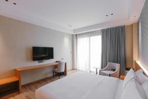 大雅台Hotel Casiana Tagaytay Managed by HII的酒店客房配有一张床、一张书桌和一台电视。