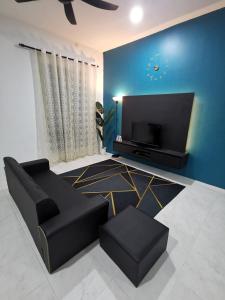 斯里伊斯兰德LYNN HOMESTAY SERI ISKANDAR的客厅配有黑色沙发和平面电视。