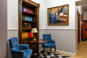 利沃夫肖邦酒店的一间设有桌子和两把蓝色椅子的房间,以及一幅画
