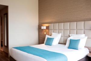 阿尔泽特河畔埃施Residhome Luxembourg Esch-Belval的卧室配有带蓝色枕头的大型白色床