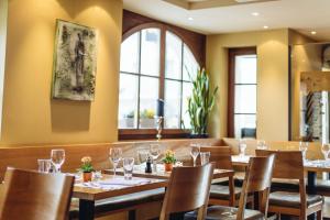 伦策海德斯贝克查酒店的餐厅设有木桌、椅子和窗户。