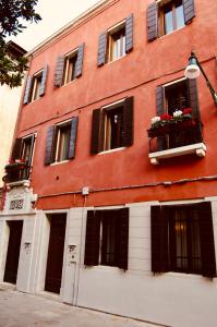 威尼斯Ca' del Pittor Apartments的一座红色的大建筑,窗户上装有窗户和鲜花