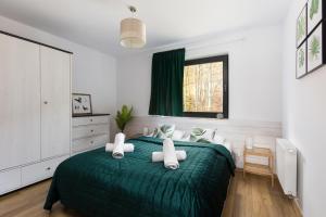 什切尔克APARTAMENT SKANDYNAWSKI 2-poziomowy SAUNA JACUZZI的一间卧室设有一张绿色的床和一个窗户。