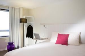 里尔里尔中心贝法火车站宜必思尚品酒店的一张带粉红色枕头的白色床和一台笔记本电脑
