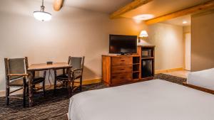 姊妹城Best Western Ponderosa Lodge的酒店客房配有一张床、一张书桌和一台电视。