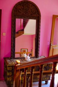 桑给巴尔Garden Lodge的粉红色墙壁的房间的一张桌子上的镜子