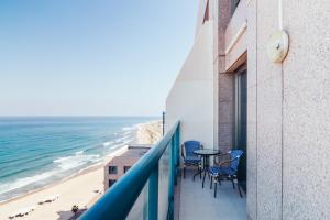 海法Almog Haifa Israel Apartments מגדלי חוף הכרמל的一个带桌椅和海滩的阳台