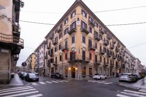 都灵Hotel Montevecchio的一条城市街道上的大型建筑,有车辆停放
