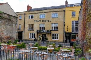 韦尔斯The Swan Hotel, Wells, Somerset的酒店前面设有桌椅