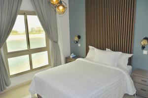 阿可贺巴Amwaj Resort For Families Only的卧室配有白色的床和窗户。
