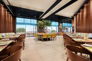 阿吉曼Wyndham Garden Ajman Corniche的餐厅设有木桌和椅子以及大窗户。