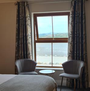 Annagry凯斯琳奥尔酒店的卧室设有窗户、两把椅子和一张桌子