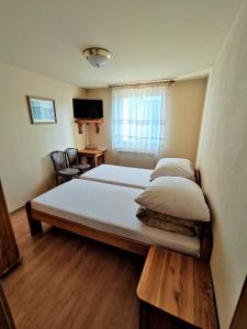 Heľpa卢卡斯旅馆的一间卧室设有两张床、一张桌子和一个窗口。