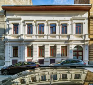 布达佩斯RES City Residence Hotel Budapest的一座白色的建筑,前面有汽车停放