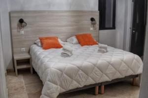 San-Gavino-di-CarbiniA PIANARELLA的一张白色大床,上面有橙色枕头