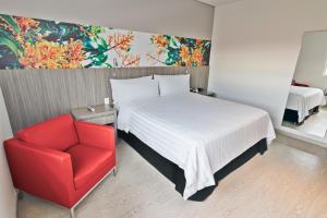 内瓦GHL内瓦酒店的一间卧室配有一张床和一张红色椅子
