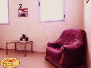 贝尔谢巴阿拉丁贝尔谢巴酒店的一张红色的皮椅,放在带桌子的房间