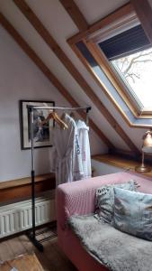 莱克凯尔克Theetuin Onder de Pannen的阁楼间设有粉红色的沙发和窗户。