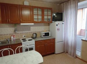 新西伯利亚1к. Апартаменты НСК на ул.Блюхера 67/1的厨房配有木制橱柜和白色冰箱。