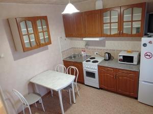 新西伯利亚1к. Апартаменты НСК на ул.Блюхера 67/1的厨房配有桌子、炉灶和冰箱。