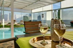 因赫尼奥Los Cipreses的两杯白葡萄酒在桌边的游泳池边