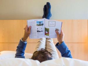 洛桑洛桑克里西尔宜必思酒店的躺在床上看书的人