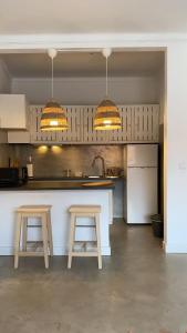 科武港Porto Covo Bay House的厨房配有2把凳子、1个柜台和2盏灯