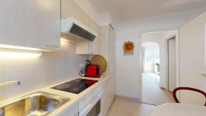 圣莫里茨Plattas 9的厨房配有白色橱柜、水槽和炉灶。
