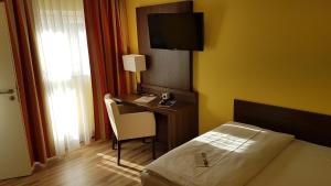 纽伦堡纽伦堡英维特酒店的一间卧室配有一张床和一张书桌及电视