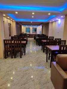 加德满都Pashupati View Hotel的餐厅设有木桌和椅子,灯光蓝色