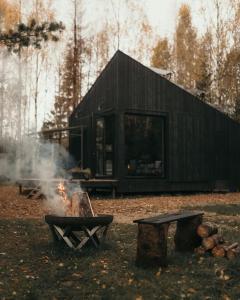 利加特内Briežu Stacija Off Grid Cabin的前面有一个火的黑色小屋