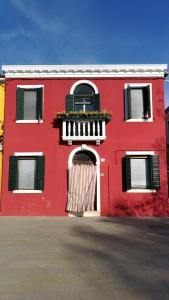 布拉诺岛Casa degli Artisti的红色的建筑,设有门和阳台