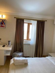 姆茨赫塔Hotel 12 Tve的一间卧室配有一张床、一张书桌和一个窗户。