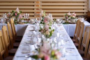 海因岑贝格吉罗斯汀伯格酒店的一张长桌子,上面有眼镜和鲜花