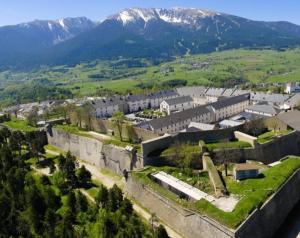 圣皮耶尔代勒福尔卡Logement cosy au pied des pistes的一座古老的城堡,以城镇和山脉为背景