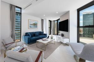 悉尼Meriton Suites Sussex Street, Sydney的客厅配有蓝色的沙发和电视