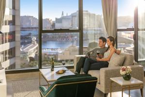 悉尼Meriton Suites Sussex Street, Sydney的坐在客厅沙发上的男女