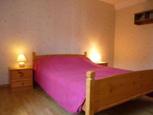 Bény-sur-Mer全面翻修5人老屋的一间卧室配有一张带紫色床罩的木床