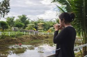 Ban Noen Hom诺普勒凯亚花园度假屋的池塘前用手机说话的女人