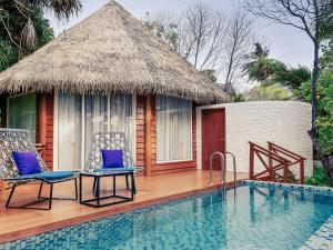 加弗阿利夫环礁Mercure Maldives Kooddoo Resort的一座带游泳池和两把椅子的度假村,毗邻一座房子