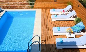 VathiEtoile Villa Heated Pool的一个带游泳池、两把躺椅和一个游泳池的甲板